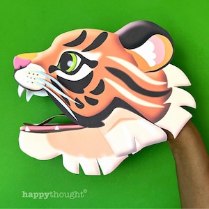 May include: A tiger puppet with an orange and black striped face, pink ears, and a white mouth with teeth. The puppet is made of paper and is held by a hand.