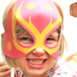 May include: Three children wearing colorful wrestling masks. The masks are made of paper and have a star design. The children are smiling and looking at the camera.