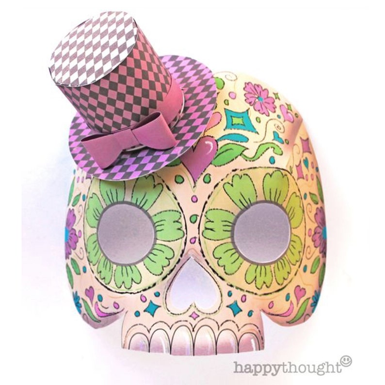 May include: A papercraft sugar skull mask with a pink and gray top hat. The mask is decorated with colorful flowers and patterns.
