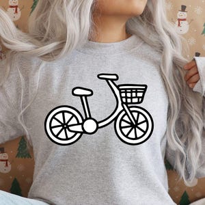 K&ouml;nnte beinhalten: Ein graues Sweatshirt mit einem wei&szlig;en Umriss eines Fahrrads mit einem Korb auf der Vorderseite.