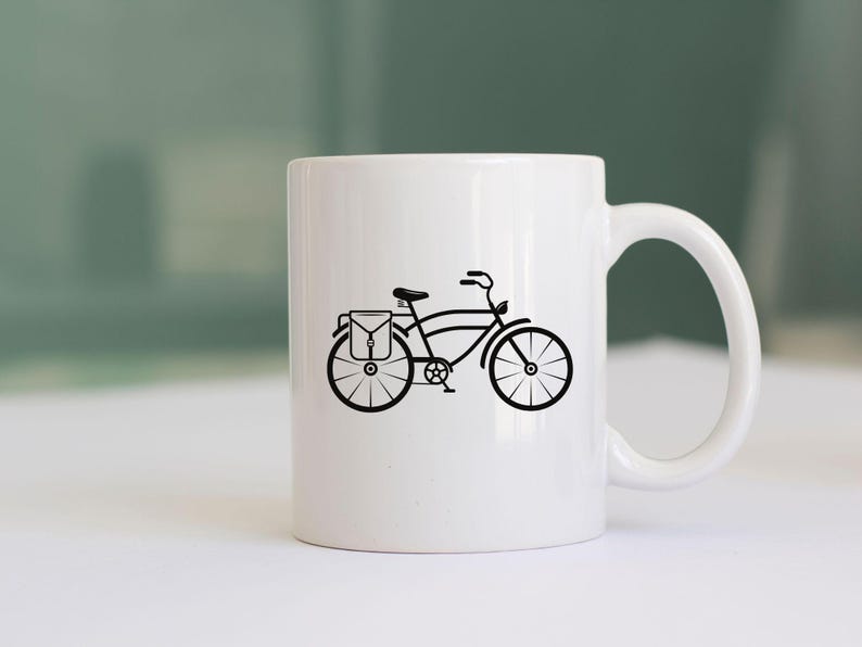 K&ouml;nnte beinhalten: Wei&szlig;e Keramiktasse mit einer schwarzen Silhouette eines Fahrrads mit einer Tasche auf dem Gep&auml;cktr&auml;ger.