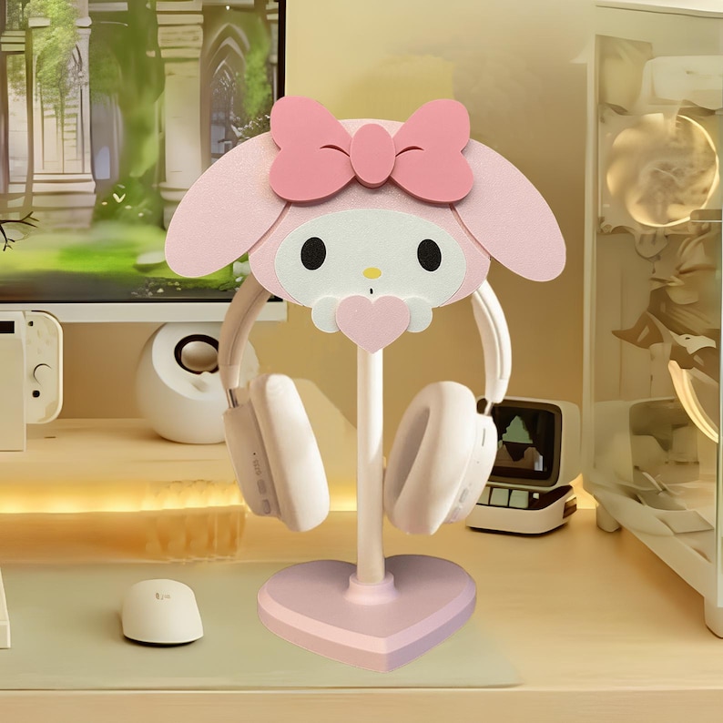 May include: Pink Hello Kitty themed headphone stand with a heart-shaped base. The stand is made of wood and features a cute Hello Kitty design.