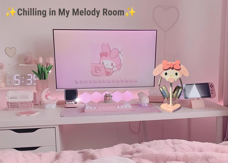 May include: A pink and white themed desk setup with a computer monitor displaying a cartoon character, a keyboard, a mouse, a headset stand, and a pink and white headset. The text "Chilling in My Melody Room" is written in the top left corner of the image.