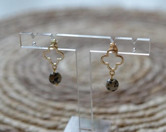 May include: Gold clover-shaped earrings with a dangling round dalmatian jasper stone.