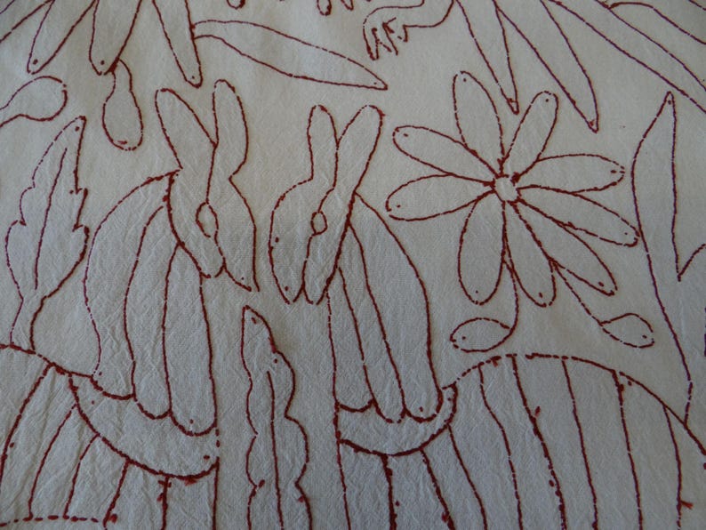 K&ouml;nnte beinhalten: Cremefarbener Stoff mit einem sich wiederholenden Muster aus roten Umrissen. Das Design umfasst stilisierte Kaninchen, Blumen und Bl&auml;tter. Das Kunstwerk hat einen Volkskunststil.