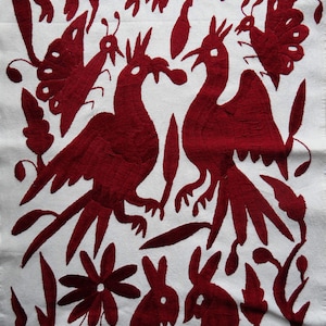 K&ouml;nnte beinhalten: Wei&szlig;er Stoff mit detaillierter roter Stickerei, die stilisierte V&ouml;gel, Schmetterlinge, Blumen und Kaninchen darstellt. Das Design im Folk-Art-Stil verwendet roten Faden, um einen auff&auml;lligen Kontrast zum wei&szlig;en Hintergrund zu erzeugen. Sehr detaillierte Stickerei.