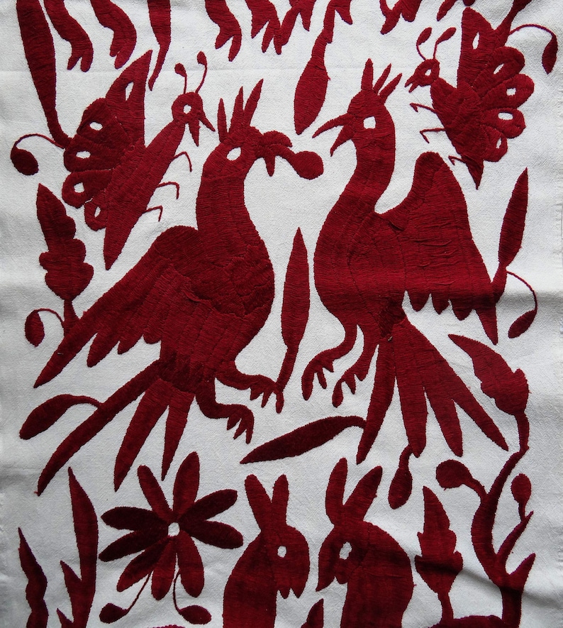 K&ouml;nnte beinhalten: Wei&szlig;er Stoff mit detaillierter roter Stickerei, die stilisierte V&ouml;gel, Schmetterlinge, Blumen und Kaninchen darstellt. Das Design im Folk-Art-Stil verwendet roten Faden, um einen auff&auml;lligen Kontrast zum wei&szlig;en Hintergrund zu erzeugen. Sehr detaillierte Stickerei.