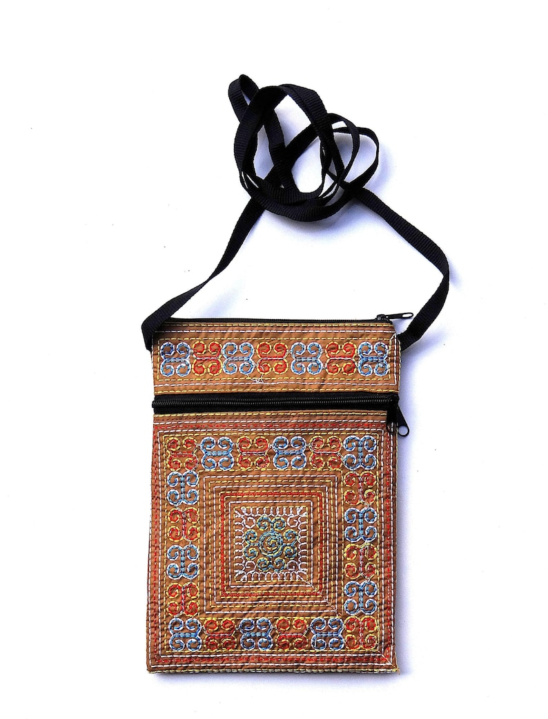 Puede incluir: Bolso bandolera rectangular marr&oacute;n con cremallera y correa negras. El bolso presenta un dise&ntilde;o bordado detallado en rojo, azul y amarillo. La correa es un simple cord&oacute;n negro.