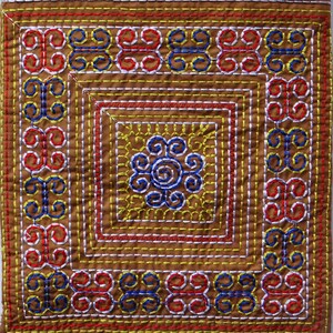 Puede incluir: Textil cuadrado con intrincados bordados en tonos marr&oacute;n, rojo, amarillo, azul y blanco. El dise&ntilde;o presenta un motivo floral central y patrones geom&eacute;tricos repetidos en los bordes. La costura es detallada y precisa.
