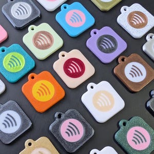 May include: A collection of square-shaped tags featuring a circular center with a Wi-Fi signal icon. These tags come in a variety of solid, glittery, and speckled finishes, including colors like pink, blue, green, orange, purple, black, and white.