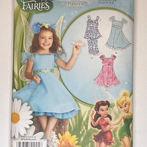 Op de afbeelding: Een Simplicity-naaipatroon voor een Disney Fairies-jurk. Het patroon is voor maten 3-8 en bevat instructies voor het maken van een blauwe jurk met een geruite rok, een roze jurk met een geruite rok en een blauw-witte jurk met een geruite rok en een bijpassende broek. Het patroon bevat ook instructies voor het maken van een feeënkostuum.