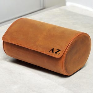 May include: A brown leather watch roll with the initials "AZ" embossed on the side.