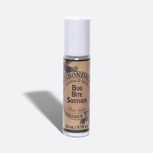 Puede incluir: Un frasco roll-on de "Bug Bite Soother" con tapa blanca. La etiqueta es de color beige con texto negro y una ilustración de pino. El frasco contiene 9,75 ml de producto.