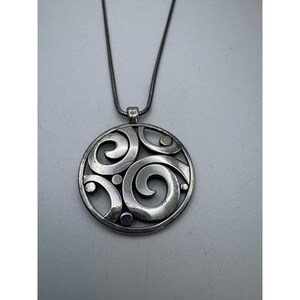 以下が含まれることがあります： 渦巻き模様と小さな円形のアクセントが特徴の、シルバーカラーのペンダントネックレス。ペンダントは、お揃いのシルバーチェーンから吊り下げられており、シンプルながらもエレガントなアクセサリーです。ペンダントの直径は約4cmです。