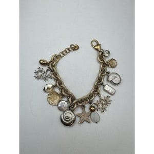 May include: A gold-toned charm bracelet featuring various ocean-themed charms. Charms include seashells, starfish, coral, and pearls. The bracelet has a lobster clasp closure and a chunky chain design.