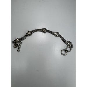May include: Silver bracelet with heart-shaped charms on a multi-strand chain. The bracelet has a toggle clasp and two decorative rings. The hearts are decorated with small, sparkling details. A charming piece of jewellery.