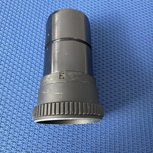 May include: A black cylindrical object with a ridged base and a smooth, glossy upper section. The object appears to be made of plastic or metal and is set against a blue textured background. The object has a small, rectangular marking.