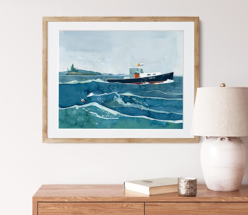 May include: A watercolor painting of a blue and white boat sailing on a choppy sea. The boat is in the foreground and the sea is in the background. The painting is framed in a light wood frame.