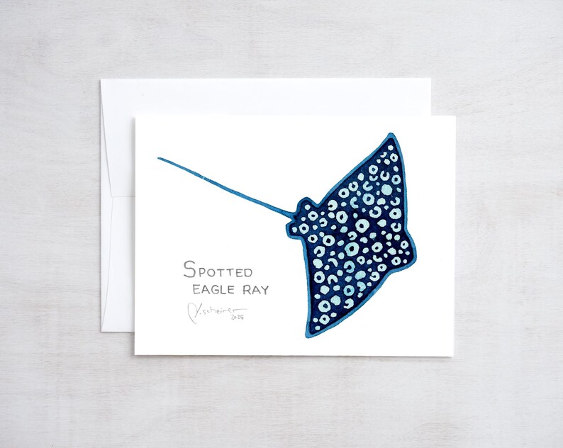 May include: A watercolor illustration of a spotted eagle ray in shades of blue and white. The image is on a white card with the text "Spotted Eagle Ray" and a signature. The card is inside a white envelope.