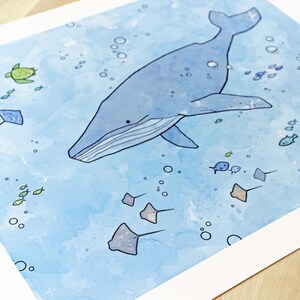May include: A watercolor painting of a blue whale swimming in the ocean. The whale is surrounded by small fish, a sea turtle, and stingrays. The background is a light blue color with white bubbles.