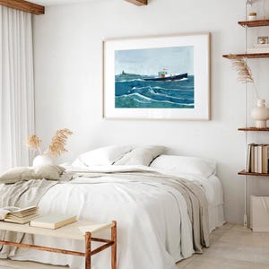 May include: A watercolor painting of a boat sailing on a blue ocean with white waves. The boat is dark blue with a white cabin and a red stripe. The painting is framed in a light wood frame and hangs on a white wall above a bed with white linens.