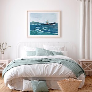 May include: A white bed with a white headboard and a white duvet cover. A blue blanket is draped over the foot of the bed. There are two blue pillows on the bed and a wicker basket on the floor next to the bed. A framed watercolor painting of a boat on the ocean hangs above the bed.