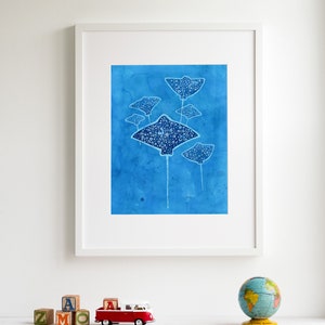 May include: A framed print of a watercolor painting featuring five blue stingrays with white spots on a blue background.