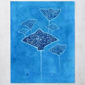 May include: A watercolor painting of five stingrays swimming in a blue ocean. The stingrays are white with black spots and have long tails.