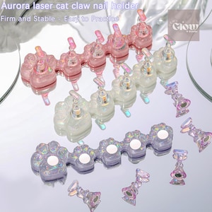 May include: Three sets of cat paw shaped nail holders in pink, white, and purple with iridescent glitter. Each set has five paw holders and comes with several small, clear nail holders. The image text reads "Aurora laser cat claw nail holder" and "Firm and Stable - Easy to Practice".