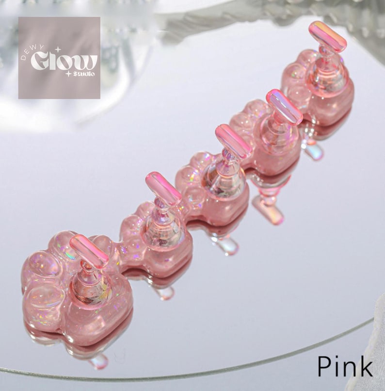 Puede incluir: Portaesmaltes de u&ntilde;as en forma de pata rosa con purpurina iridiscente. Cada portaesmaltes tiene un peque&ntilde;o portaesmaltes de metal iridiscente.