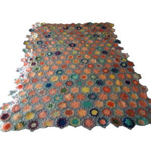 May include: A rectangular crochet blanket constructed from numerous small, circular motifs in various colors including orange, yellow, blue, green, and purple, all joined together by a light gray yarn border that creates a scalloped edge.