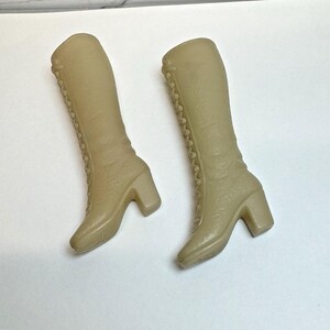 Puede incluir: Un par de botas beige de caña alta con cordones en la parte delantera y tacones gruesos.