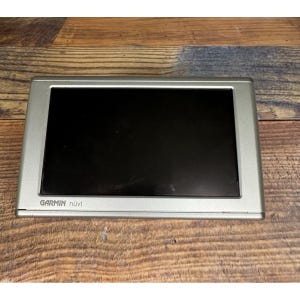 Puede incluir: Un dispositivo GPS Garmin nüvi plateado con una pantalla negra. El dispositivo tiene forma rectangular con esquinas redondeadas y un bisel plateado. El logotipo de Garmin nüvi es visible en la parte inferior del dispositivo.