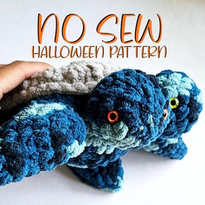 May include: Handmade crocheted turtle toys in blue and grey, with orange and yellow eyes. The text "NO SEW HALLOWEEN PATTERN" is written in orange. These plushies are ideal for Halloween.