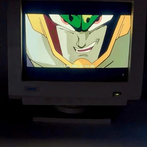 May include: A beige computer monitor displaying a close-up animation of a green and yellow character with a smirk. The screen shows the text IT'S OVER WHEN I SAY IT'S OVER in white letters at the bottom centre of the display area.