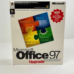 Puede incluir: Una caja de cartón blanca para el software Microsoft Office 97 Standard Edition Upgrade. El frente presenta un gráfico de rompecabezas con iconos para Word 97, PowerPoint 97, Excel 97 y Outlook 97. El texto incluye requisitos del sistema y una estrella roja.