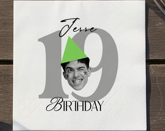May include: White square napkin with the text "Jesse 19 Birthday". The number 19 is in gray, with a photo of a smiling person wearing a green party hat. The word "Birthday" is in a script font.