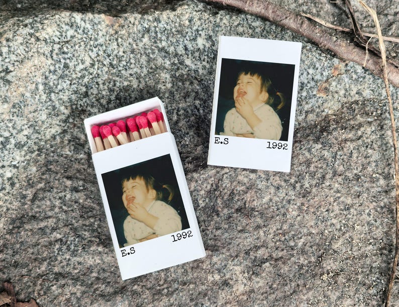 May include: White matchbox with a photo of a child eating, the text "E.S 1992" is printed below the photo. The matchbox is open, revealing red-tipped matches. A second photo with the same image and text is next to the matchbox.