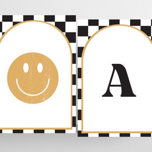 May include: Two printable wall art designs with a black and white checkered background. The first design features a gold smiley face in an arched frame. The second design features the letter "A" in black in an arched frame.