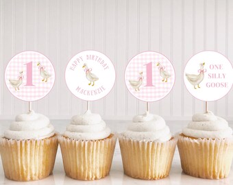 May include: Four pink and white cupcake toppers with a gingham pattern and illustrations of geese. The toppers say "Happy Birthday Mackenzie", "One Silly Goose", and "1".
