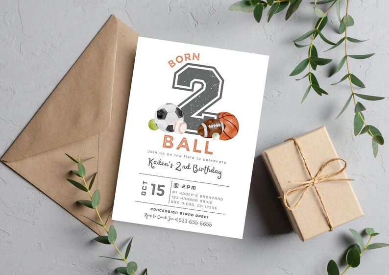 May include: A white invitation with a gray number "2" and the words "Born 2 Ball" in a brown font. The number is decorated with a soccer ball, baseball, and football. The invitation is for a 2nd birthday party and includes the date, time, and location.