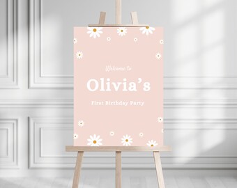 May include: A pink welcome sign with white daisies and the text "Welcome to Olivia's First Birthday Party".