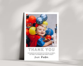 May include: A thank you card with a photo of a young child in a superhero costume surrounded by colorful balloons. The card reads "Thank you for making my birthday so special & sweet, my family & friends are hard to beat! Love. Kaden"