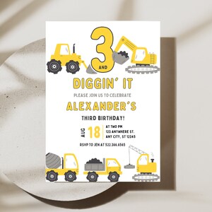 May include: A yellow and gray construction-themed birthday invitation for a boy's third birthday party. The invitation features a yellow number 3 with the words "Diggin' It" and "Alexander's Third Birthday!" The invitation also includes illustrations of construction vehicles, such as a bulldozer, excavator, and cement mixer.