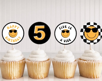 May include: Four cupcakes with decorative toppers. The toppers feature a smiley face wearing sunglasses, the number 5, and the phrases "Happy Birthday" and "Five is a Vibe." One topper has a black and white checkered background.