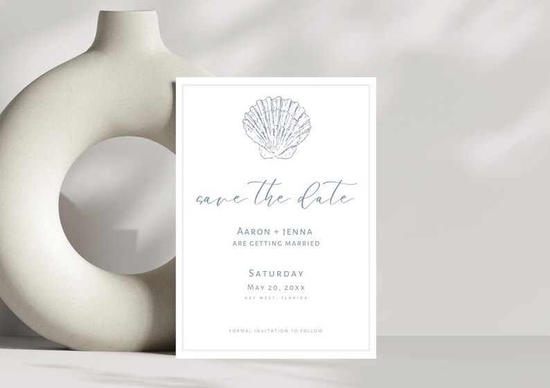 K&ouml;nnte beinhalten: Eine wei&szlig;e Save-the-Date-Karte mit einer blauen Muschel-Illustration. Der Text lautet "save the date", "Aaron + Jenna are getting married", "Saturday, May 20, 20XX", und "Formal invitation to follow".