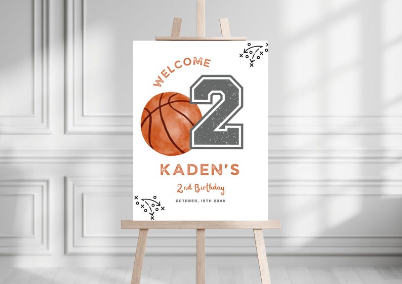 May include: A white rectangular birthday welcome sign featuring a basketball graphic, a large grey number 2, and the text WELCOME, KADEN'S, 2nd Birthday, and OCTOBER, 15TH 20XX in copper-colored lettering, accented with black sports play diagrams.
