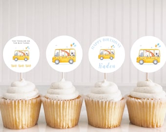 Puede incluir: Cuatro cupcakes con glaseado amarillo y forros de cupcake blancos. Cada cupcake tiene una pegatina redonda blanca con un autobús escolar amarillo con animales. Las pegatinas dicen "The Toddler on the Bus Turns", "Happy Birthday Kaden" y "Too Too Too".
