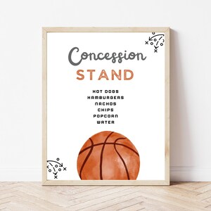 May include: A framed sign with a white background featuring the text Concession STAND in gray and orange. Below, a list includes HOT DOGS, HAMBURGERS, NACHOS, CHIPS, POPCORN, WATER. A watercolor basketball sits at the bottom with black play diagrams.