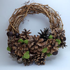 May include: A brown twig wreath decorated with pine cones, small green moss balls, and brown chestnuts.